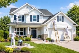 Professional exterior house painting — painters on ladders painting a white home exterior
