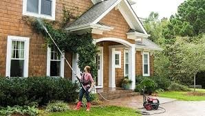 Professional pressure washing — technician cleaning home exterior with power washer